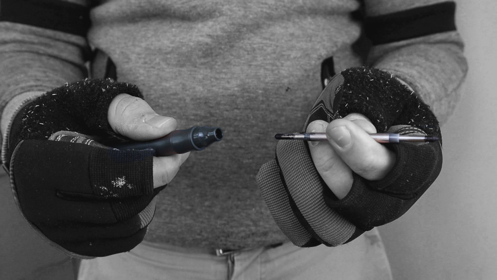 A person in black and gray winter gloves holds a separated SMART Purple Series 32mm Deep Cut Bi-metal Blade in each hand; the grayscale image highlights the gloves and blade.
