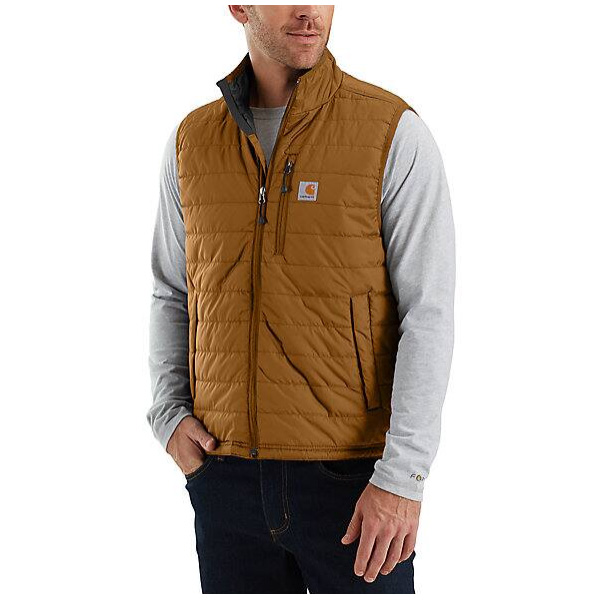 A man in a brown Carhartt insulated vest over a light gray long-sleeve shirt, left hand in pocket, stands against white background.