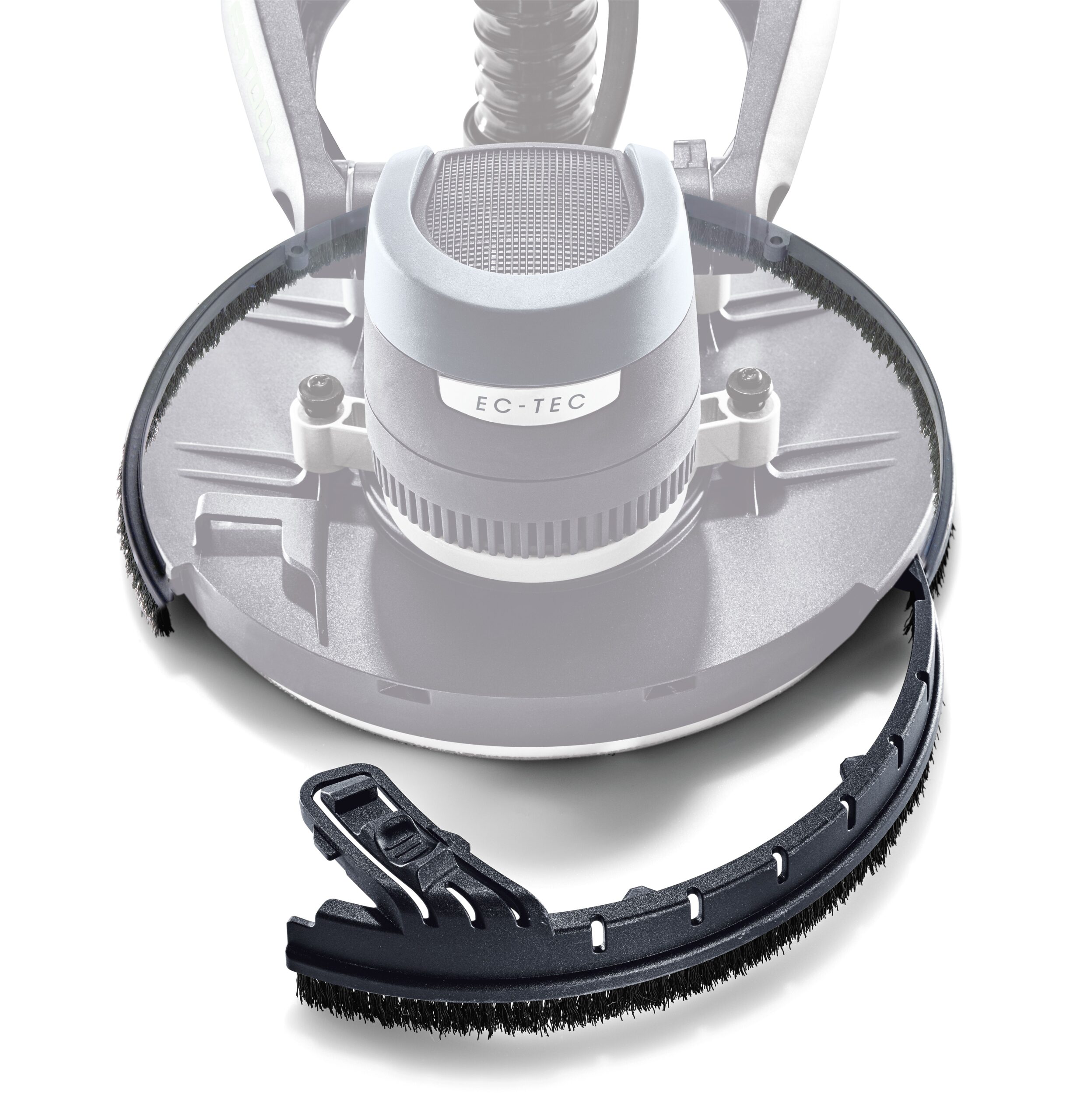 Close-up of a round power tool with a detachable black brush attachment in the foreground, the brush curving to fit its shape.