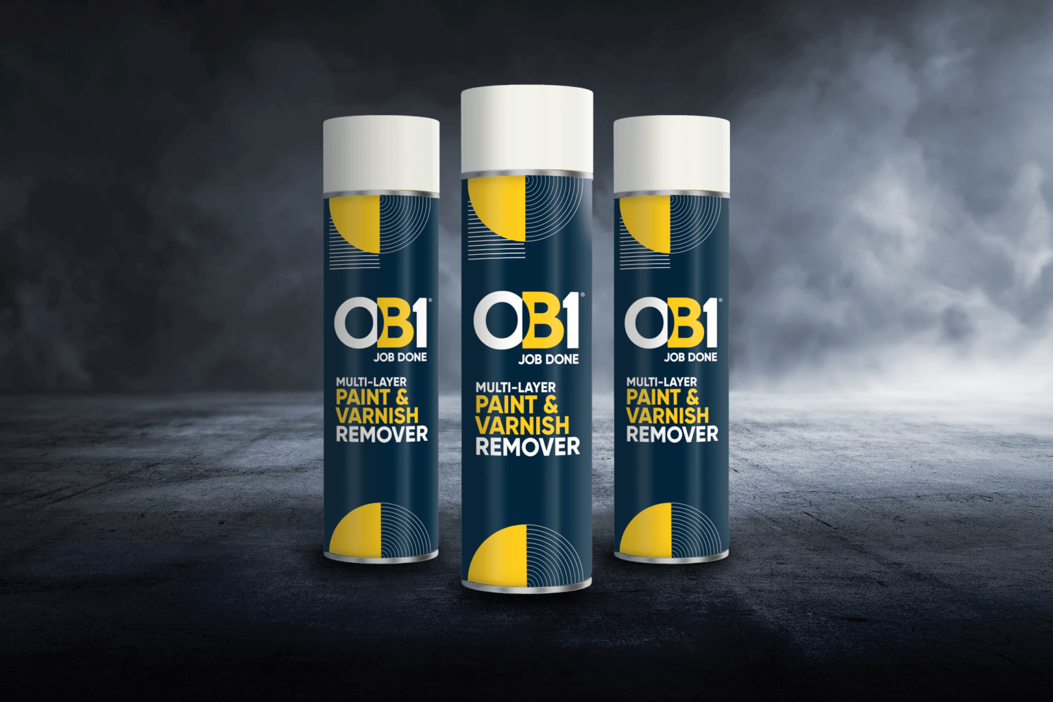 Three OB1 Multi-Layer Paint & Varnish Remover 500ml cans stand upright on a dark surface with a smoky background.