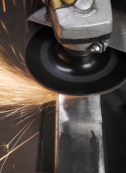 A close-up of an angle grinder cutting metal with 316492 FS966 115x22 60 grit fibre Ceramic Multibond discs and bright sparks flying.