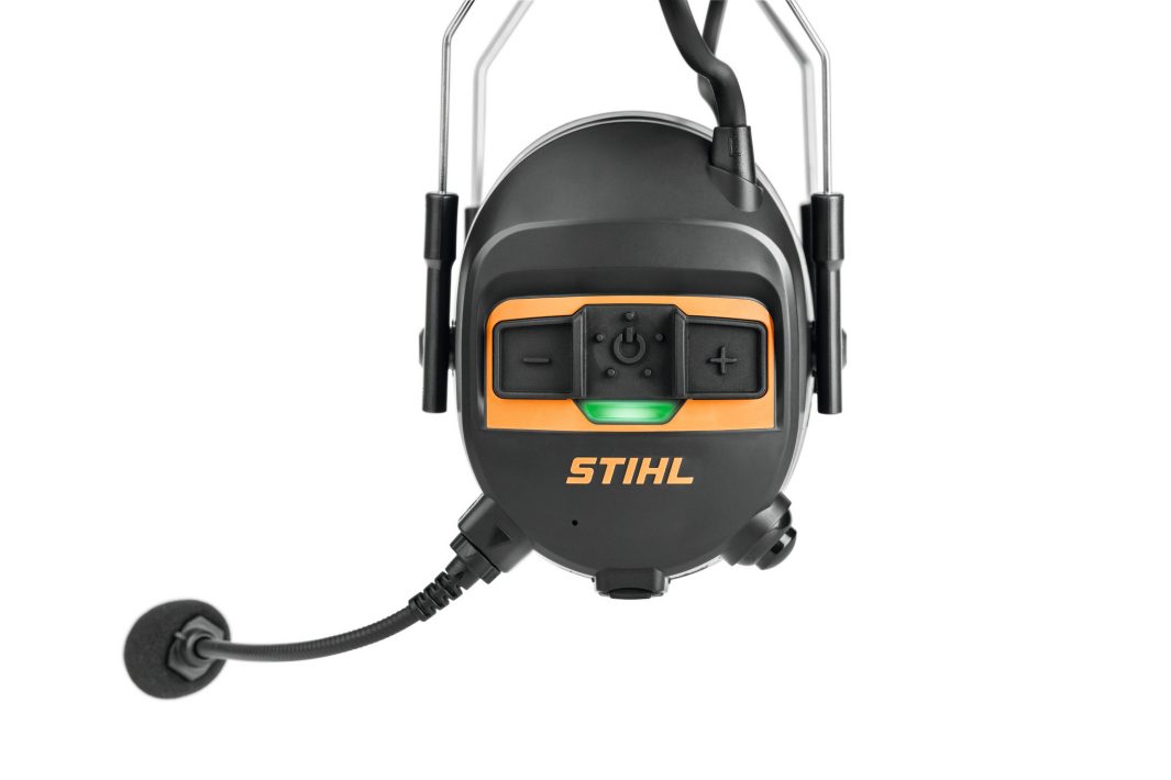 Close-up of the STIHL ADVANCE PROCOM Headset in black and orange with a microphone, volume buttons, and green indicator light.