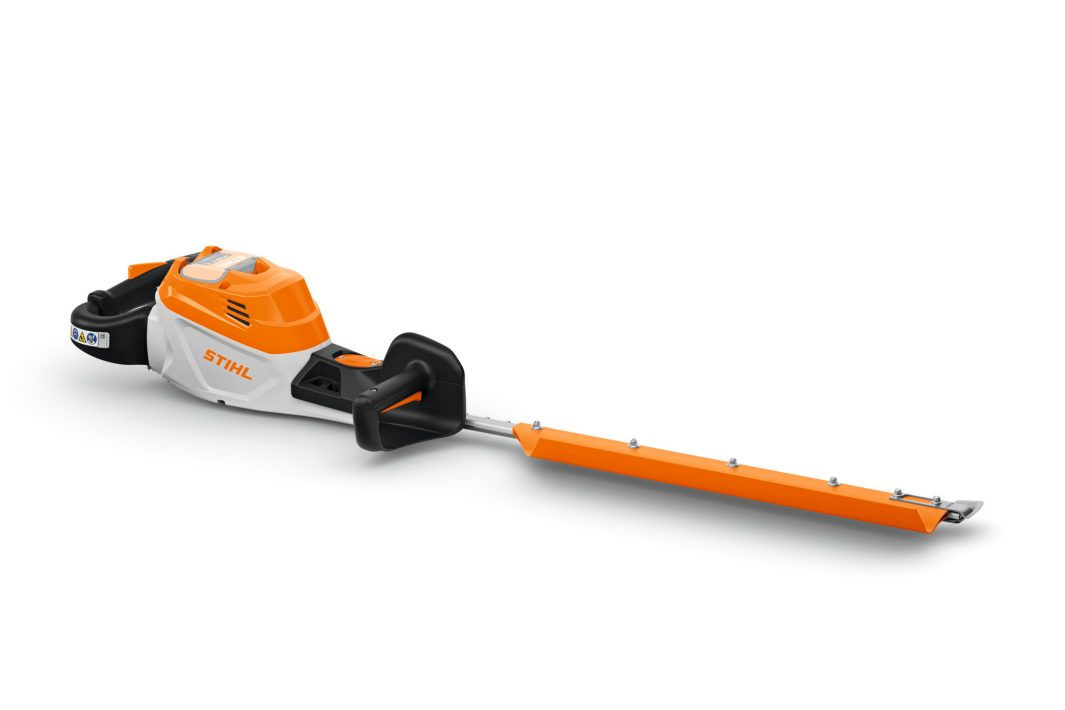 A cordless STIHL hedge trimmer with an orange and white body, black handle, and a long, covered blade on a white background.