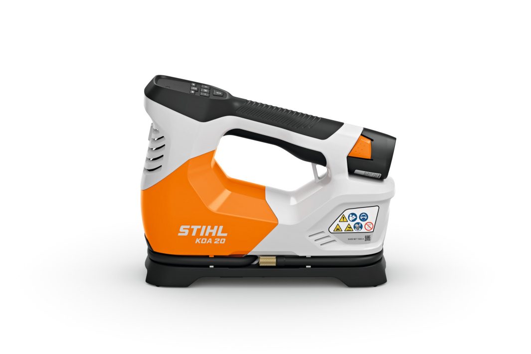 A compact, orange and white STIHL KGA 20 power tool with a black handle and safety warning labels on a white background.