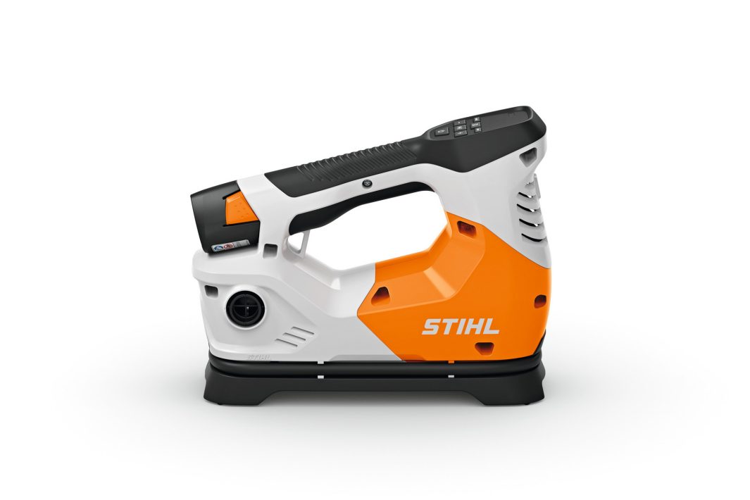 A compact STIHL pressure washer in white, orange, and black with a top handle and control panel, displayed on a white background.