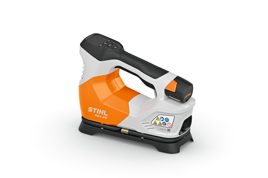 A cordless STIHL KGA 20 machine with an orange, white, and black body, digital control panel, handle, and visible safety labels.