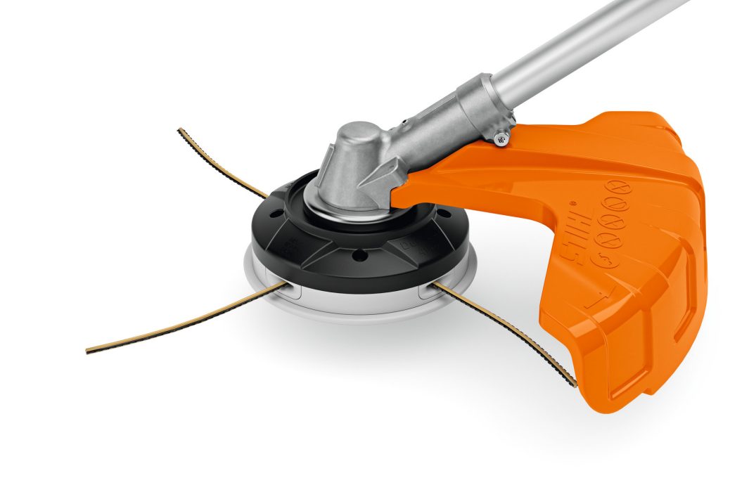 Close-up of an orange and silver strimmer head with three cutting lines and a protective orange guard for trimming grass.