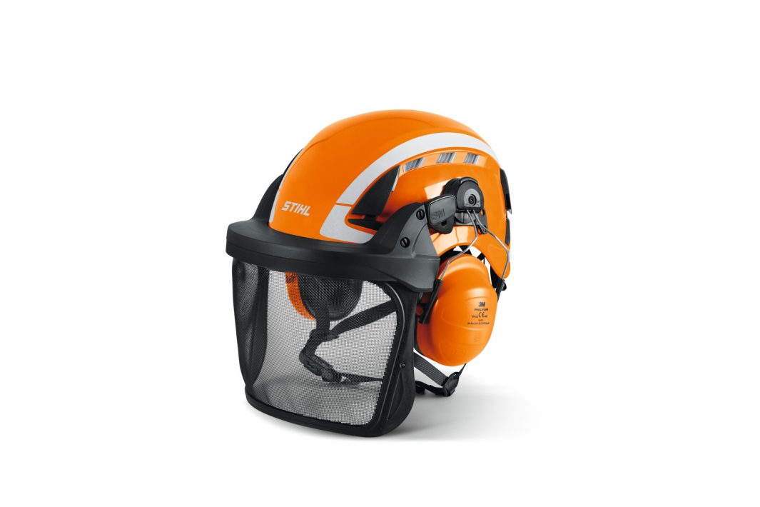 An orange STIHL safety helmet with built-in ear protection and a black mesh visor, used for forestry or outdoor work.