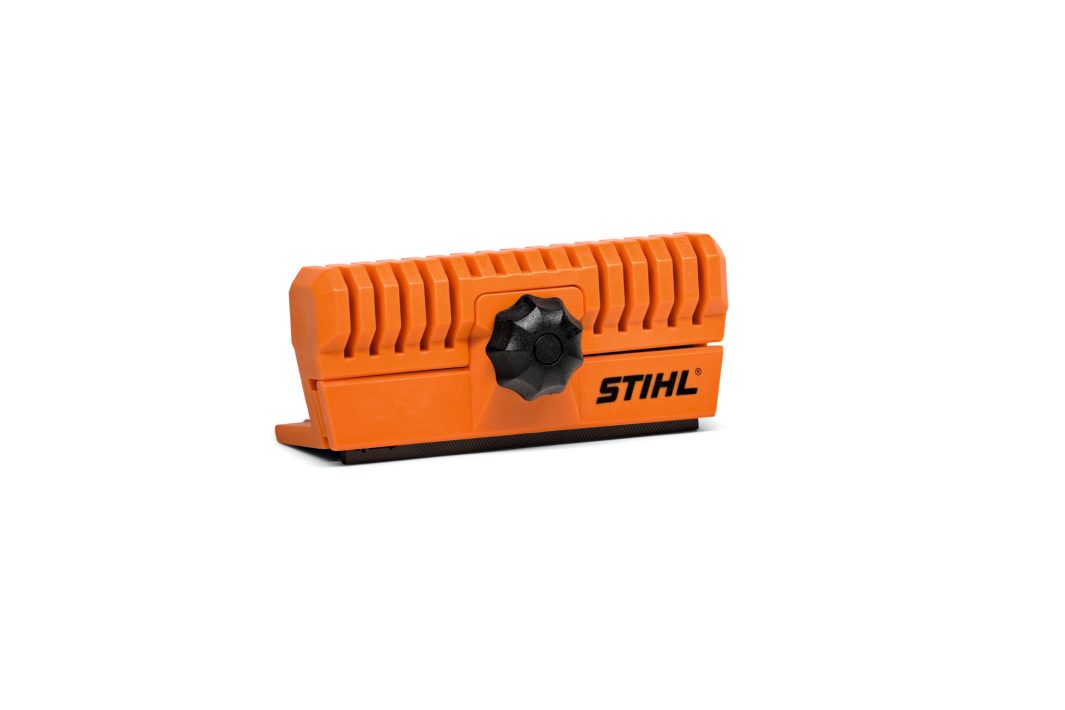 An orange blade sharpener with ribbed sides and a black turning knob in the centre, placed against a white background.