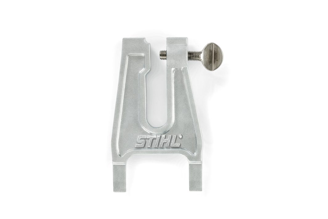 A silver metal Stihl filing vice with a screw clamp, designed to hold chainsaw chains in place for sharpening.