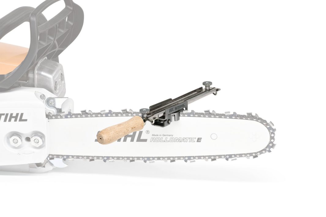 A Stihl chainsaw with a Stihl FF1 .404" × 5.5mm file guide holder with a wooden handle and metal parts for sharpening the chain.
