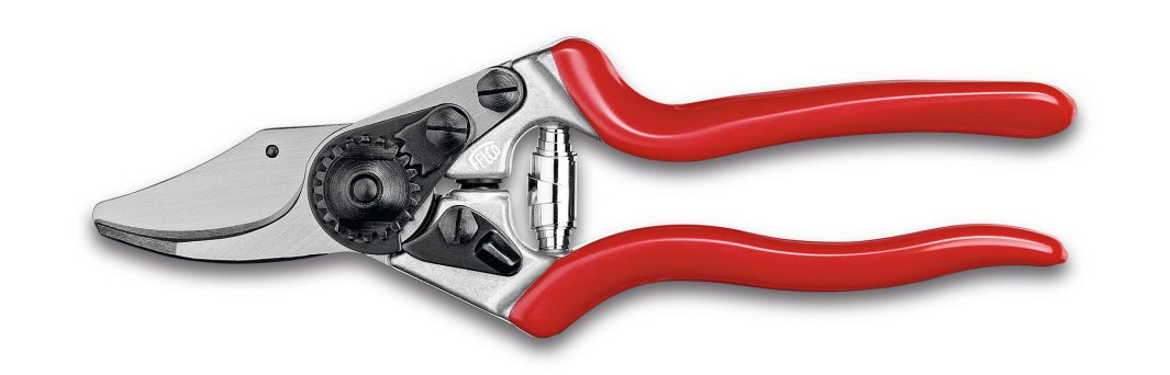 A pair of metal secateurs with red handles, a curved cutting blade, and a gear mechanism near the blade for gardening use.
