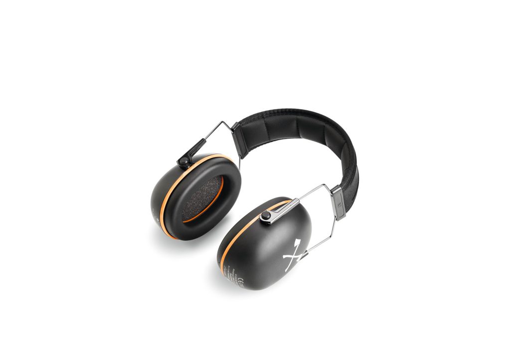Black over-ear headphones with orange trim, padded headband, and metal arms next to Stihl tinted safety spectacles on white background.