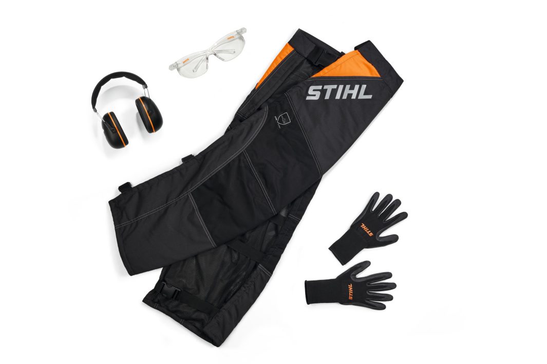 Protective gear set with Stihl HS Leg Protection in black, safety glasses, ear muffs, and black gloves on a white background.