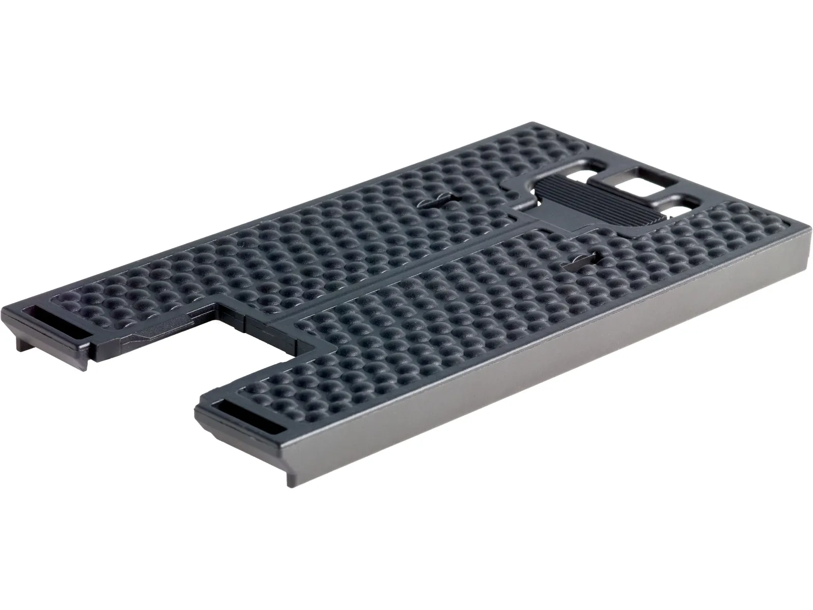 A rectangular black plastic piece with raised grid texture and notched cut-outs, likely part of an electronic or mechanical device.