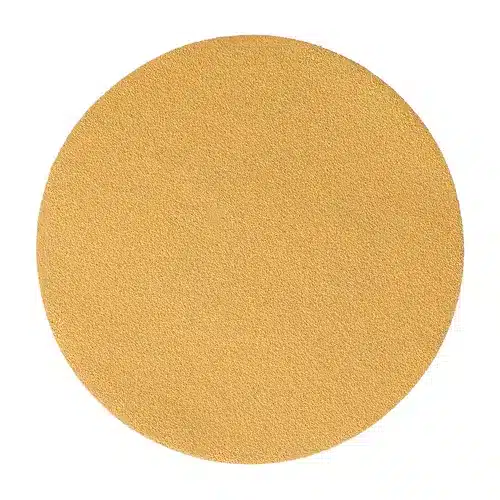A round, flat, light brown sheet of sandpaper with a fine, even texture is shown against a white background. This is one of the Mirka Gold 150mm PSA Sanding Discs (100pc), engineered for efficient and consistent sanding performance.