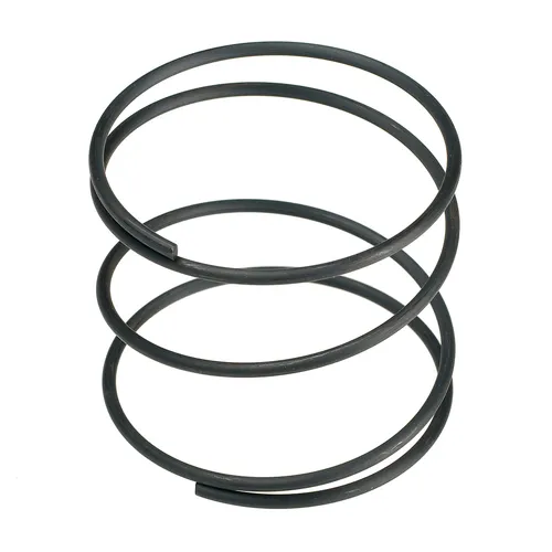 A close-up of a metal compression coil spring standing upright on a white background, shown next to a Mirka Carbon Brush+Cap Kit No. 76+78 for Miro 955/955-S for detailed comparison.