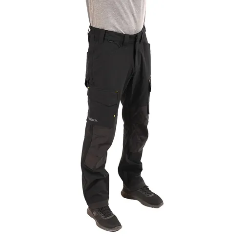 A person wearing black Mirka® Work Trousers Signature, a grey t-shirt, and black shoes stands with arms out of frame against a white background.
