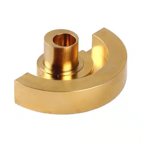 Gold-coloured, semi-circular metal component with a raised cylindrical centre and a hole through the top, possibly a machine or mechanical part.