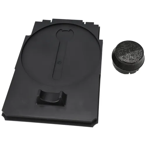 Black rectangular plastic tray featuring a circular raised section and a handle, placed beside a small round black textured disc on a white background.