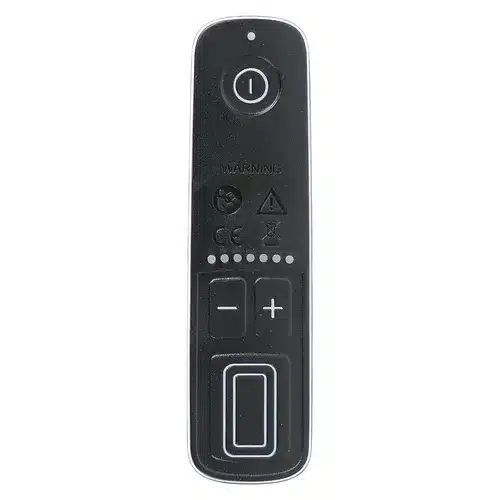 A black remote control with a round power button at the top, plus and minus buttons, and a large rectangular button at the bottom. Various warning symbols are visible in the centre.