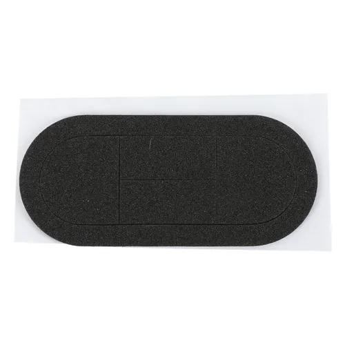 Black, oval-shaped adhesive patch with a textured surface, placed on a white rectangular backing. The patch has precut lines dividing it into smaller shapes within the oval.