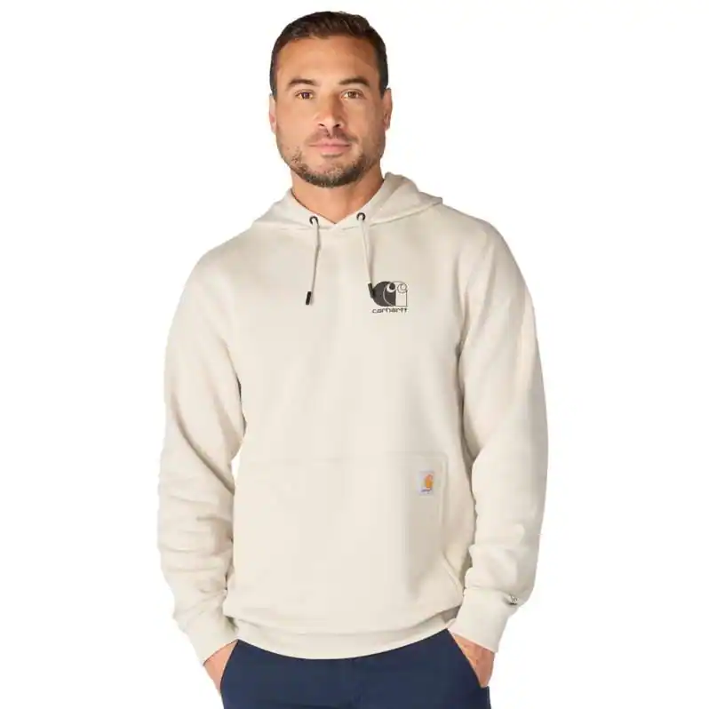 A man stands with his hands in the front pocket against a plain white background, wearing the Carhartt M Force Logo Sweatshirt in the Cobblestone colourway, which features a light beige tone and a small logo on the chest, paired with dark blue trousers.