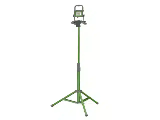 A green and grey tripod stand with adjustable height supports a small rectangular LED work light at the top. The legs are extended outward for stability.