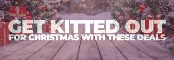 Snowy wooden path between decorated Christmas trees and wrapped presents, creating a festive and wintry atmosphere with blurred lights in the background.